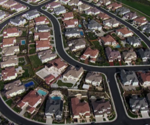 Aerial view of a neighborhood of houses with a Discovery Channel bug in the bottom right corner
