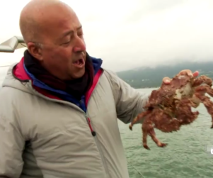 Travel Channel Bizarre Foods Host Andrew Zimmern on a boat holding a large crab